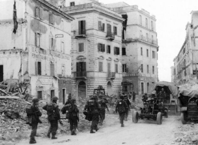 Tropas de la 1st British Division marchan entre los escombros por una calle de Anzio. 22 de enero de 1944
