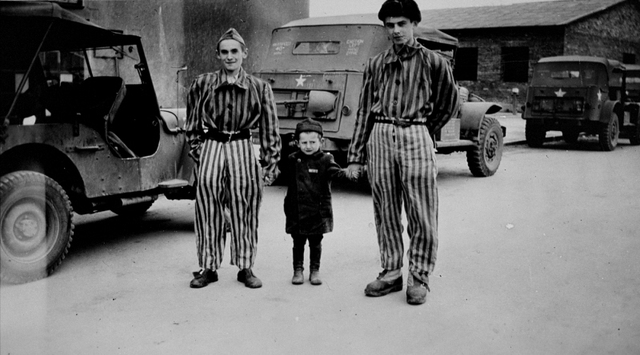 El niño superviviente Joseph Schleifstein posa con dos jóvenes vestidos con uniformes de los campos de concentración en Buchenwald