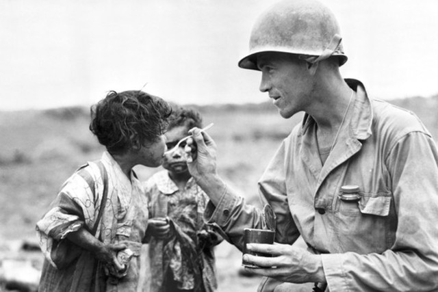 Un soldado estadounidense comparte sus raciones con dos niños japoneses en Okinawa